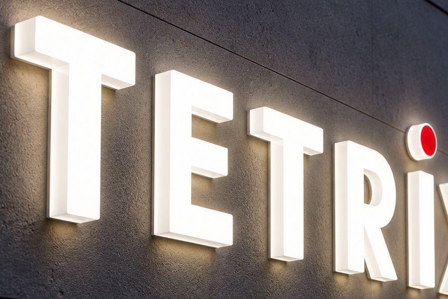 Stora vita upplysta 3D-bokstäver som bildar TETRIX på en grå fasad
