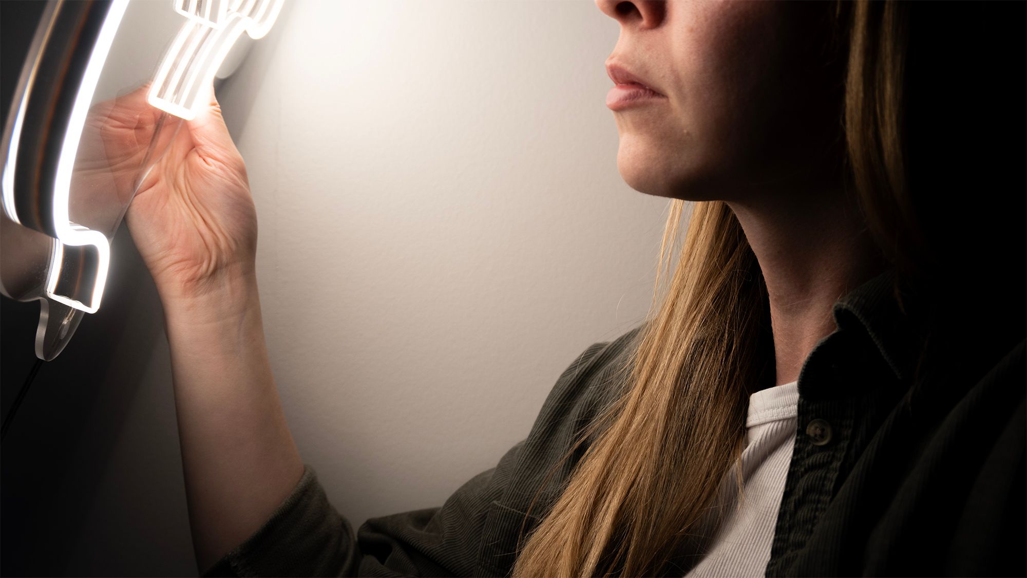 Kvinna som monterar en vit LED-neonskylt på en vägg